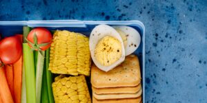 A neatly packed bento lunchbox featuring a mix of global snacks on a wooden table.