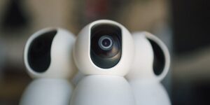 A modern smart home sensor device sitting on a shelf in a clean, bright living room.