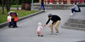 A calm parent supporting their toddler in a peaceful public park setting.