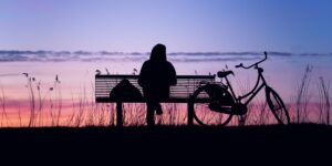 A peaceful urban park scene at sunset with a person reading on a bench, conveying the essence of Quiet Tourism.