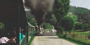 Vintage steam train traveling through a scenic mountain valley in autumn.