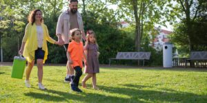 A family entering a vibrant urban park on a sunny day.