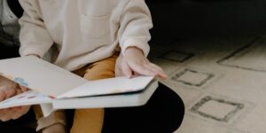 A parent and toddler reading a book about emotions together in a cozy living room.