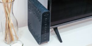 A modern home office desk featuring a mesh WiFi router.