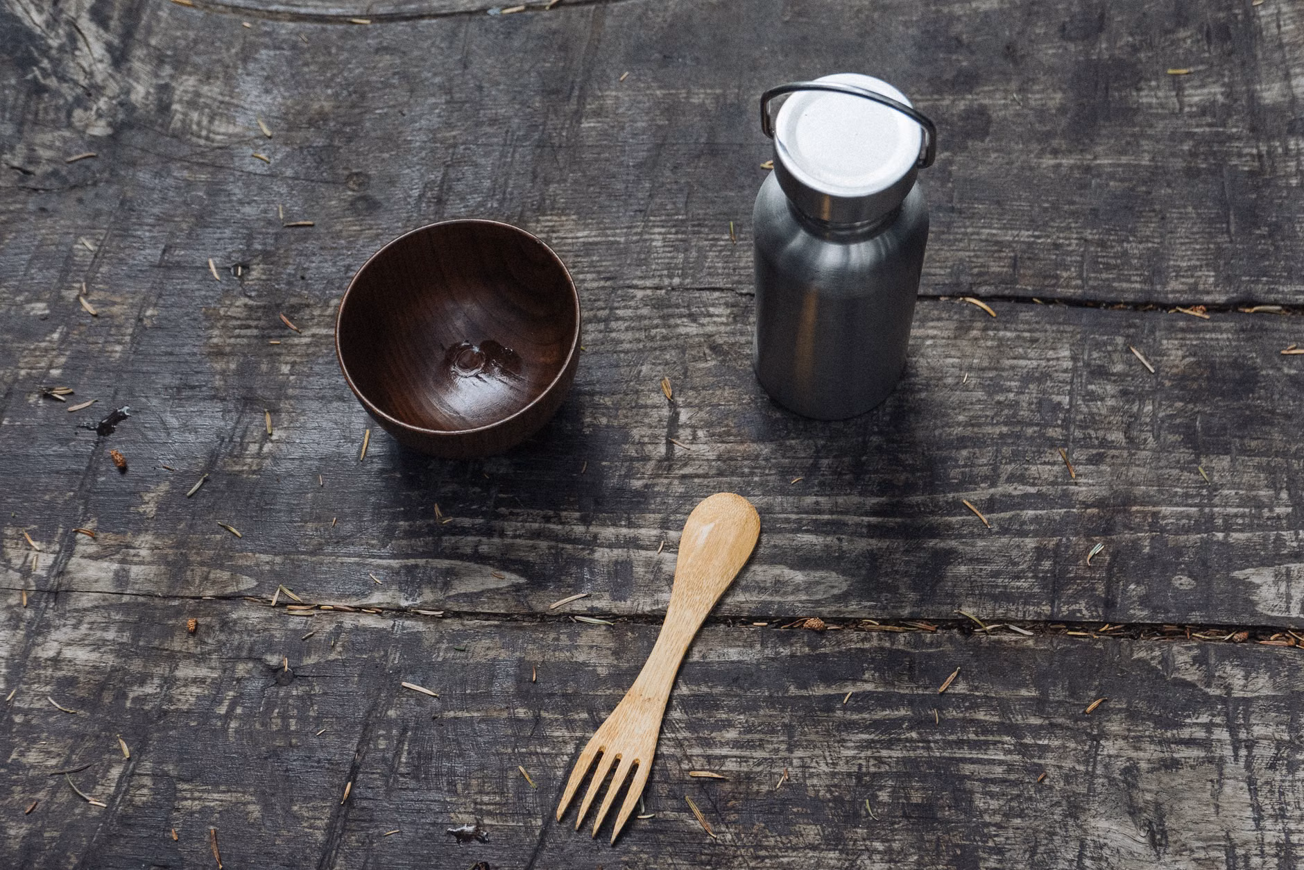 Reusable stainless steel camping kitchenware on a wooden table.