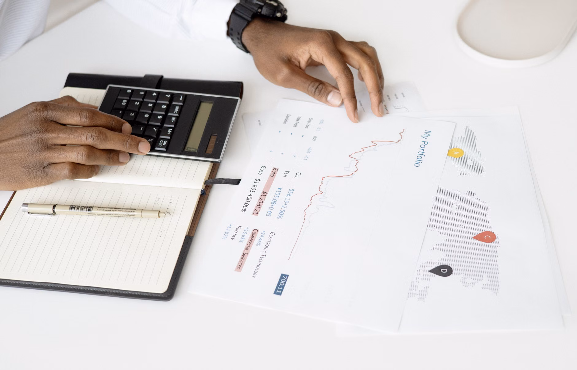 A hand calculating financial figures on a notepad.