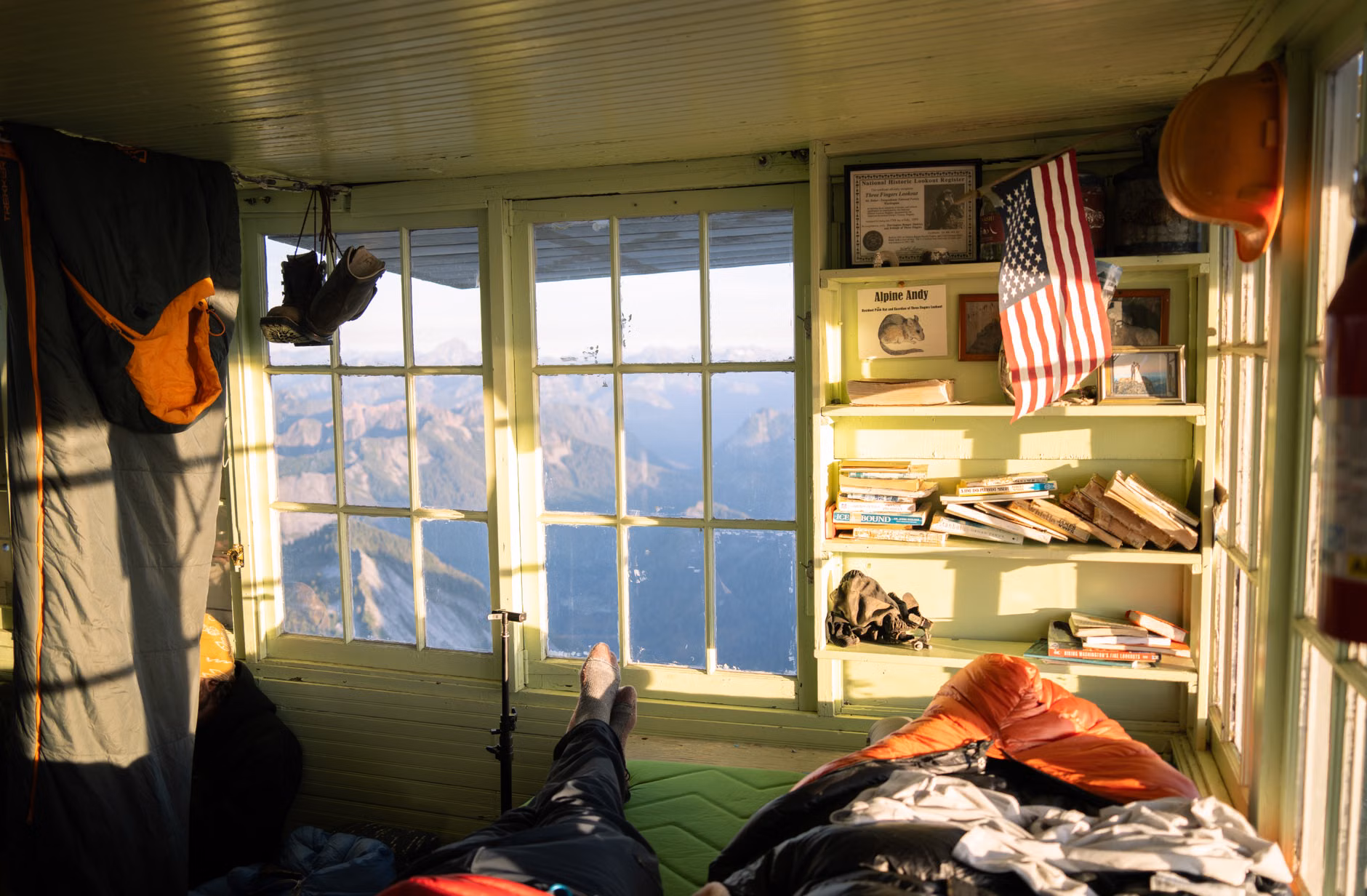 Hiking boots resting by a cabin door in the morning light.