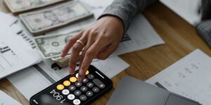 A person reviewing digital expenses on a smartphone at a desk.