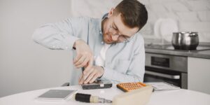 A person repairing a smart thermostat at a kitchen table.