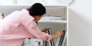 A person reconfiguring a modular shelving unit in a sunlit living room.