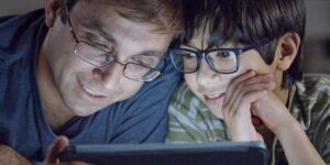 A parent and child looking at a tablet together in a cozy living room setting.