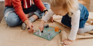 Parent and child playing a financial literacy board game together at home.