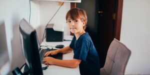 A 10-year-old child focused on digital media at a desk.
