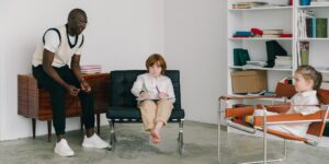 A parent facilitating a calm discussion between two school-age children at a kitchen table.