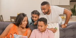 A diverse family engaging in conversation in a modern, shared living space.