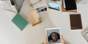 Hands holding a vintage photo next to a tablet showing a family tree.