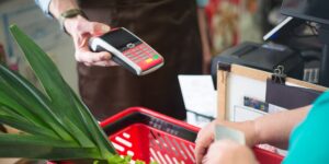 A calculator sitting next to a basket of fresh groceries on a kitchen counter.