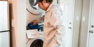 A person performing maintenance on a home appliance in a modern kitchen.
