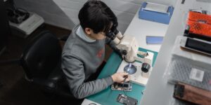 A person repairing a smartphone at a kitchen table, representing the shift toward consumer-led electronics maintenance.
