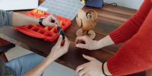 A person repairing a modular smartphone on a wooden desk.