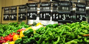 A modern grocery store aisle with fresh produce and price tags.