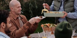 A group of adults enjoying a communal dinner at a long table in an industrial-style pop-up space.