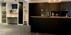 A sleek E-Paper family calendar mounted on a kitchen wall in a modern home.