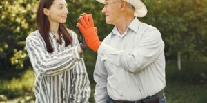 An elderly man and a young child gardening together in a sunlit community center.