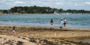 A family walking along a harbor on a car-free island during a sunny vacation.