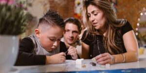 A parent guiding two children through a creative problem-solving activity at home.