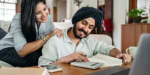 A couple planning their finances for a nomadic lifestyle with laptops and documents.